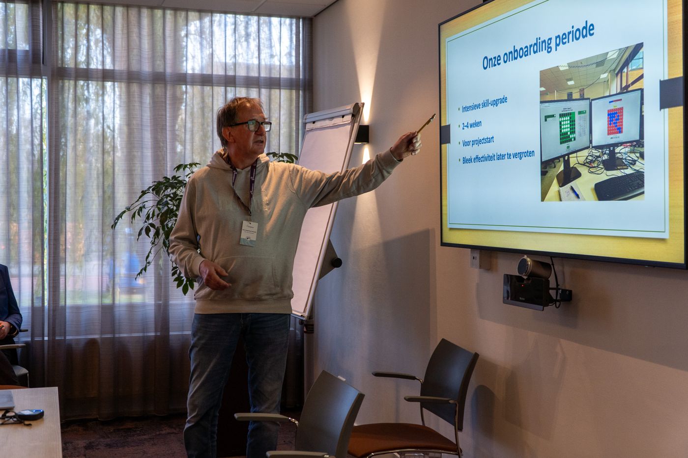 Een spreker geeft een presentatie bij het scherm