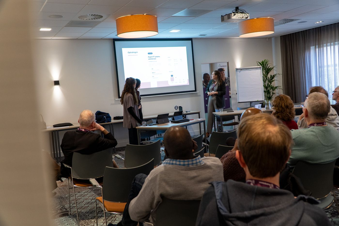 Deelnemers volgen een sessie in een van de zalen